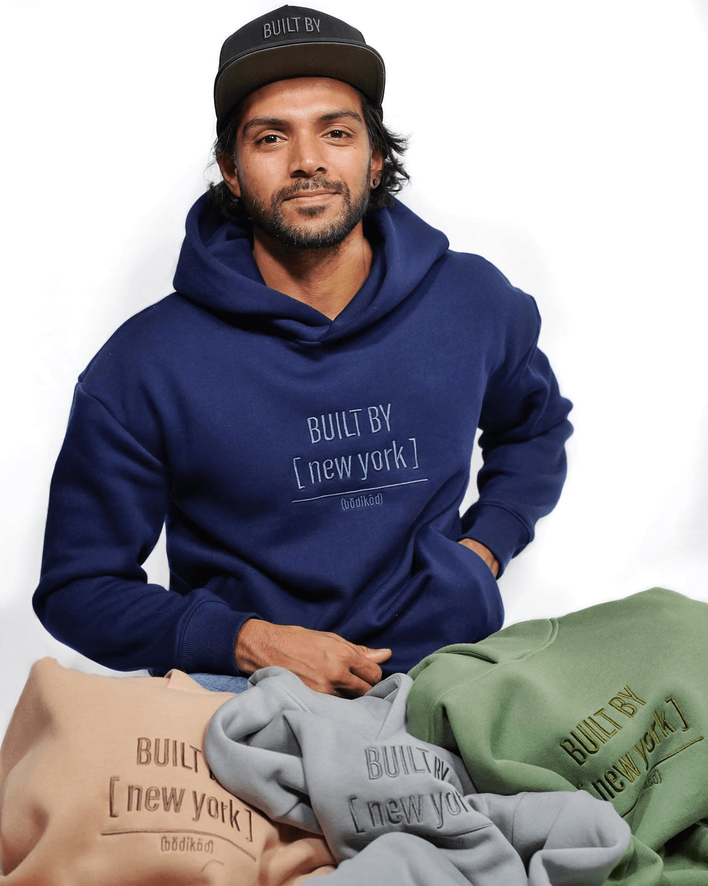 Sage Ashique in a BUILT BY [ new york ] hoodie surrounded by product